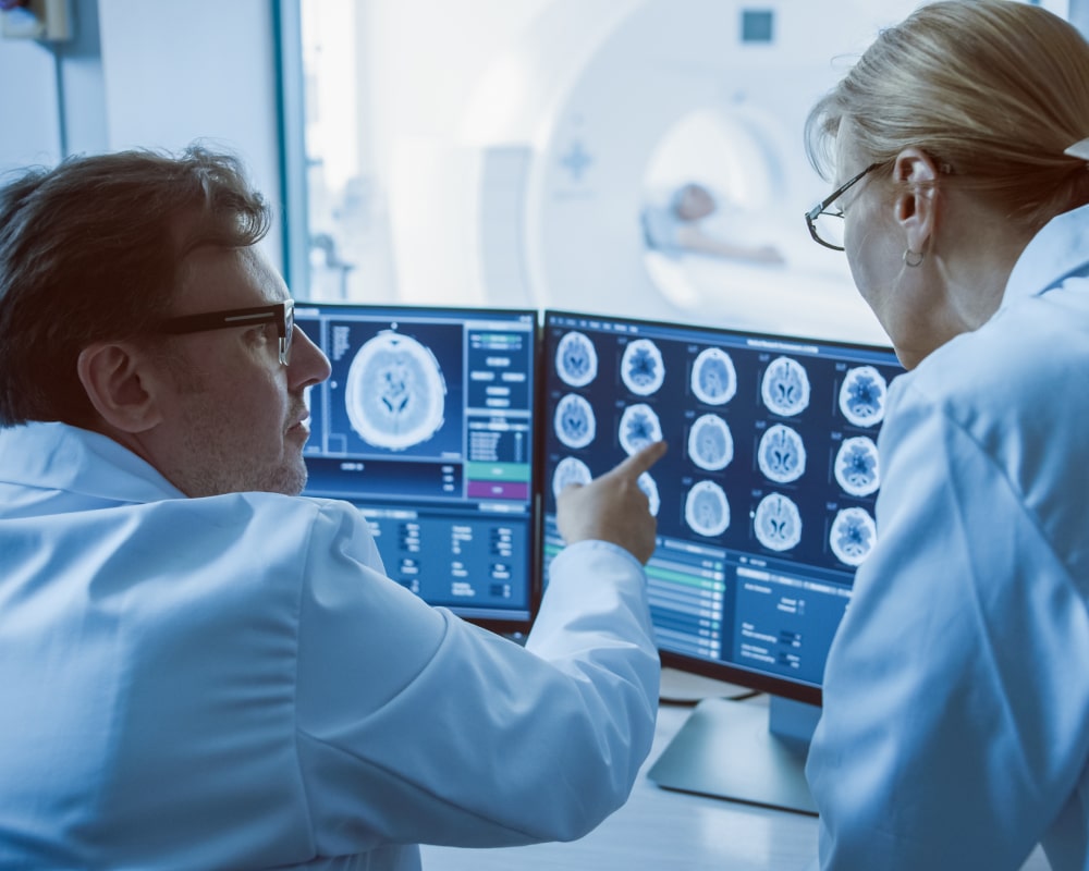 Two scientists looking at brain scans on a computer screen
